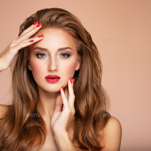 Model with fashion makeup.. Face of young woman with red lipstick and long brown hair. Stock